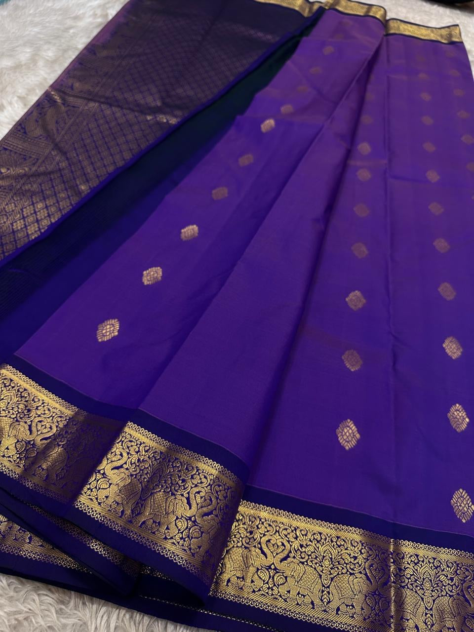 Vadamalli Yaanai – Pure Kanchipuram Silk Saree
Royal purple body with delicate gold zari floral medallion buttas
Ornate yaanai procession borders with vine detailing in zari
Ships in two weeks silk mark certified