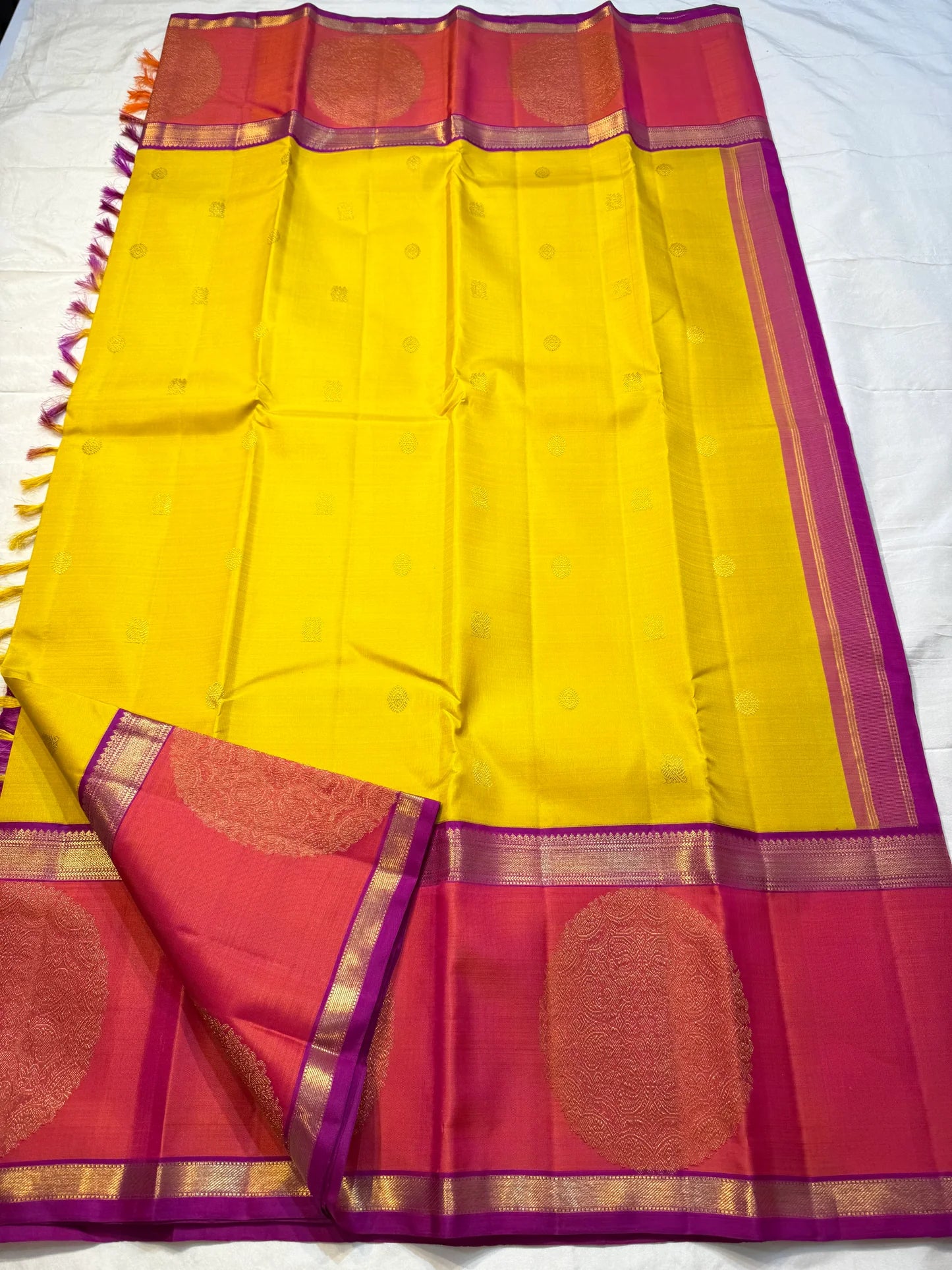 Mangai Manjal Chakram — Kanchipuram Pure Silk
Sun-yellow body with tiny zari buttas • Korvai contrast border
Rani-pink shot with purple selvedge • chakram medallions
Vaira-oosi diamond pallu with dual-tone tassels
Silk Mark Certified • Free shipping