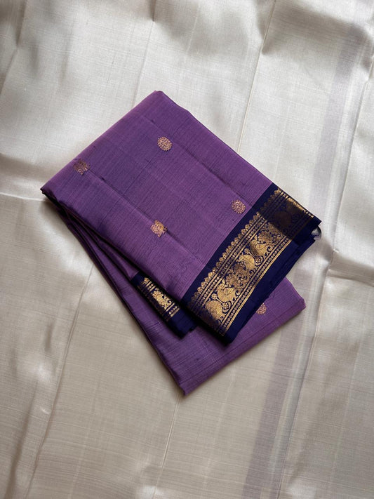 Lilac Mayil Pushpam – lilac-purple body with navy korvai borders
Pure Kanchipuram silk • gold zari pushpam (flower) buttas all over
Grand navy brocade pallu with diamond jaal • contrast blouse with border
Silk Mark Certified | Fall & Pico Done |
