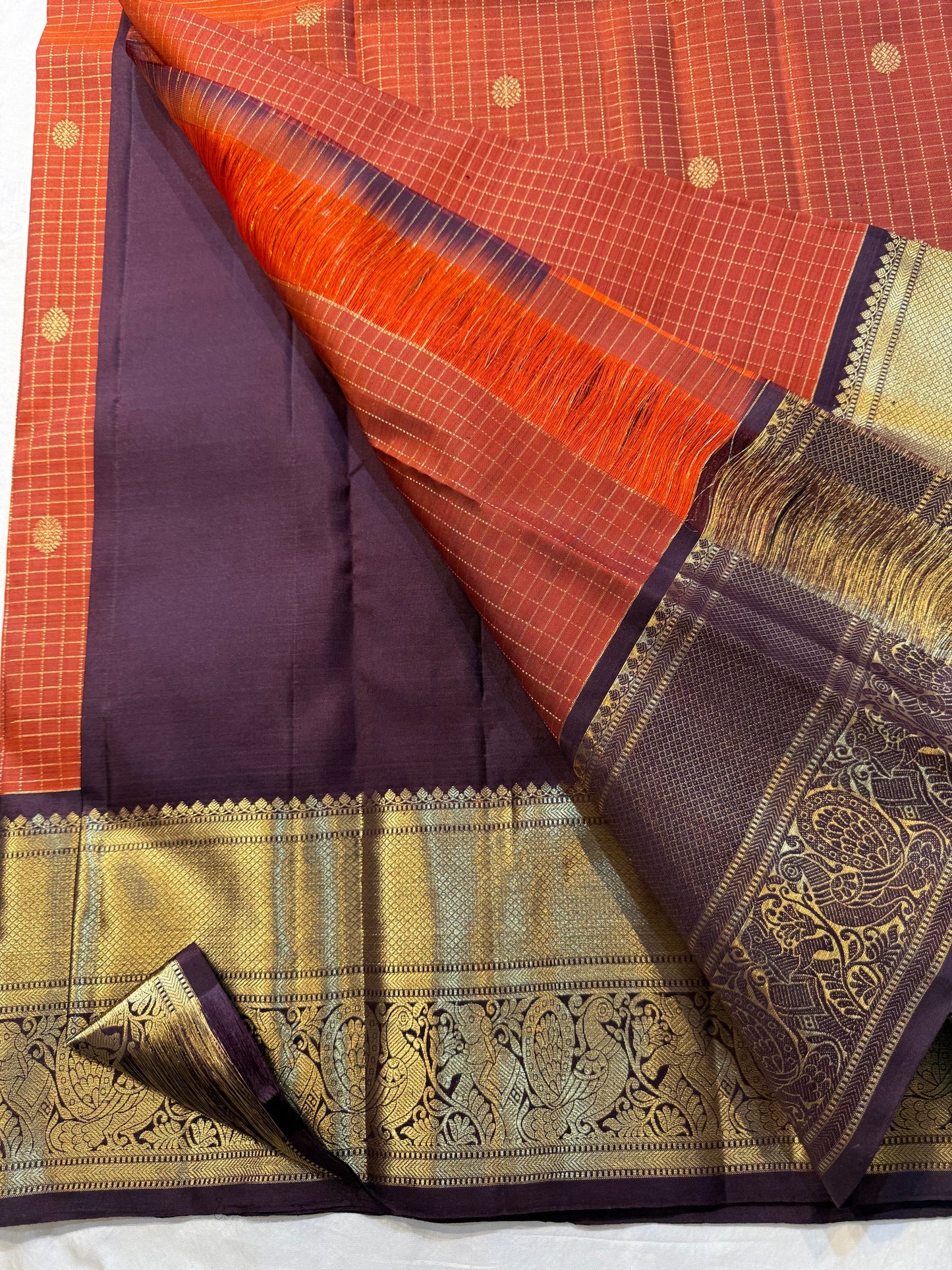Rust Orange Kattam & Purple Korvai – Pure Kanchipuram Silk Saree
Rust-orange checks with delicate gold buttas and contrast purple korvai borders
Grand purple zari-pallu | Contrast purple blouse | Fall & Pico Done
Silk mark certified ships