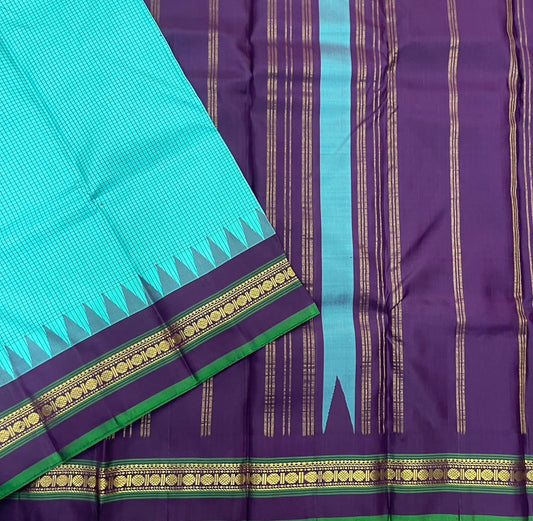 Gopura Neelam — Kanchipuram Pure Silk Saree
 
 
Teal-green body with micro kattam checks for a sleek drape
Regal aubergine korvai border with gopuram/temple motifs & gold zari
Parrot-green selvedge for a fresh, festive pop of contrast
Aubergine pall
