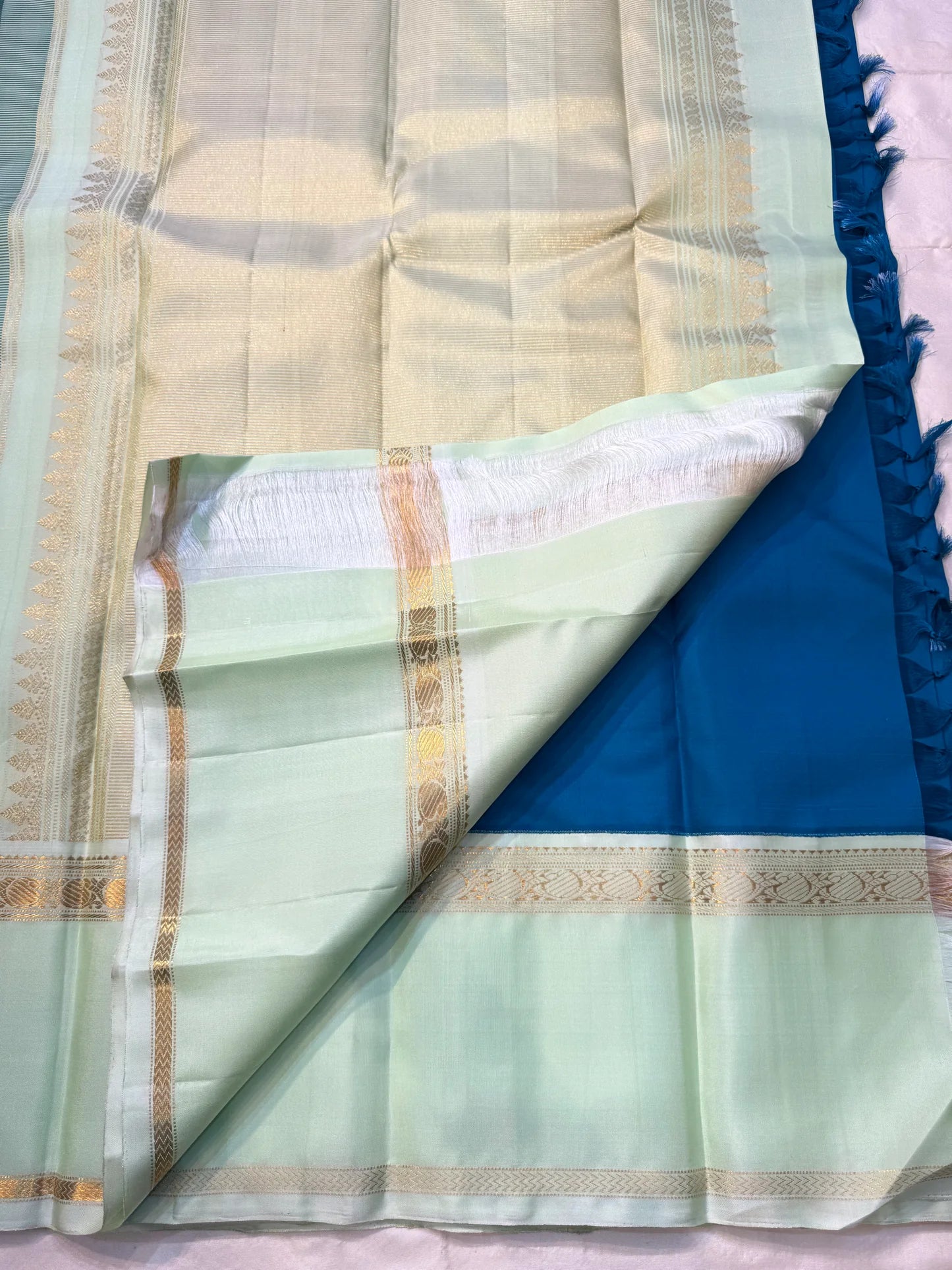 Vasantha Neelam — Teal Korvai Kanchipuram Pure Silk Saree
Peacock-blue body with gold muthu buttas · Mint-pistachio korvai border & pallū
Handloom Kanchipuram • Contrast running blouse included
Silk Mark Certified
Free Shipping within USA, 2 weeks
