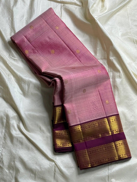 Rose Mist Zari Kattam — Kanchipuram Pure Silk
Blush rose-pink body with micro kattam (checks) in zari & scattered soorya-chakram buttas
Contrast mulberry purple korvai borders with rich gold zari detailing
Free shipping within USA silk mark certified