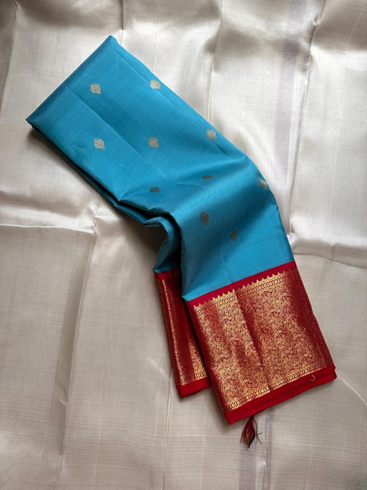 Sky blue silk saree body with small gold buttas and rich red zari woven border