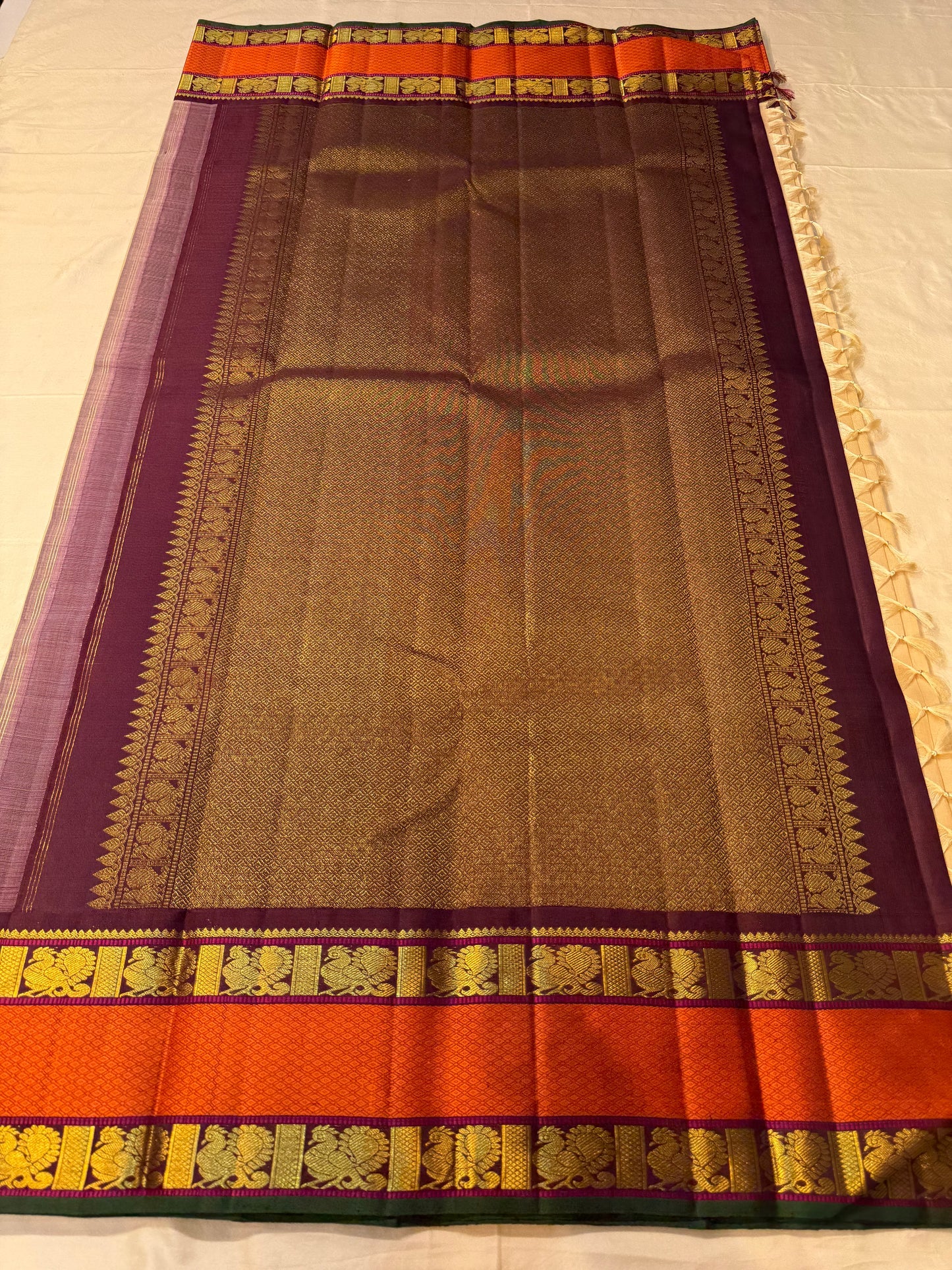 Full pallu spread of pure Kanchipuram silk saree with maroon purple zari woven pallu, gold detailing, and rust orange border, available in the USA