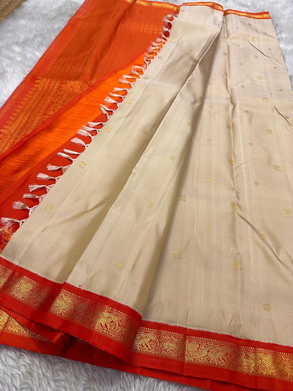 Amber Shubhra Butta — Pure Kanchipuram Silk Saree
Ivory body with golden zari buttas and vibrant amber-orange pallu
Pure 3gm zari • Silk Mark Certified • Free Shipping within USA