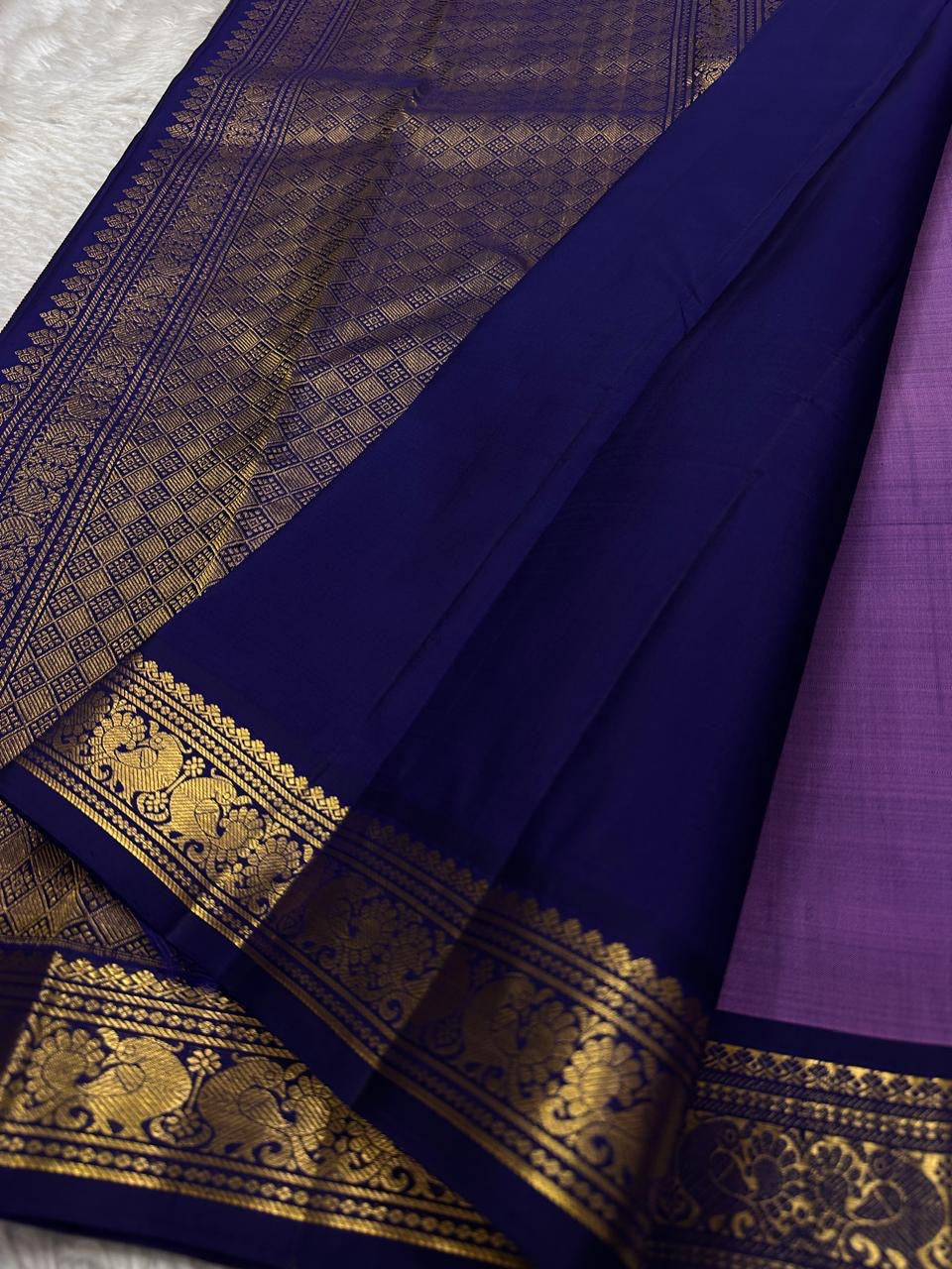 Lilac Mayil Pushpam – lilac-purple body with navy korvai borders
Pure Kanchipuram silk • gold zari pushpam (flower) buttas all over
Grand navy brocade pallu with diamond jaal • contrast blouse with border
Silk Mark Certified | Fall & Pico Done |