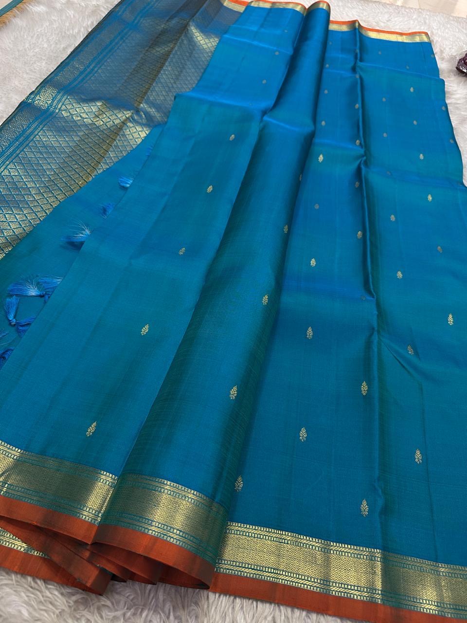 Peacock Teal Ilai Butta – serene teal body with copper-gold zari borders
Pure Kanchipuram silk • dainty leaf (ilai) buttas scattered across the body
Rich teal zari pallu
Silk Mark Certified | Fall & Pico Done | Blouse Stitching Available ($30)