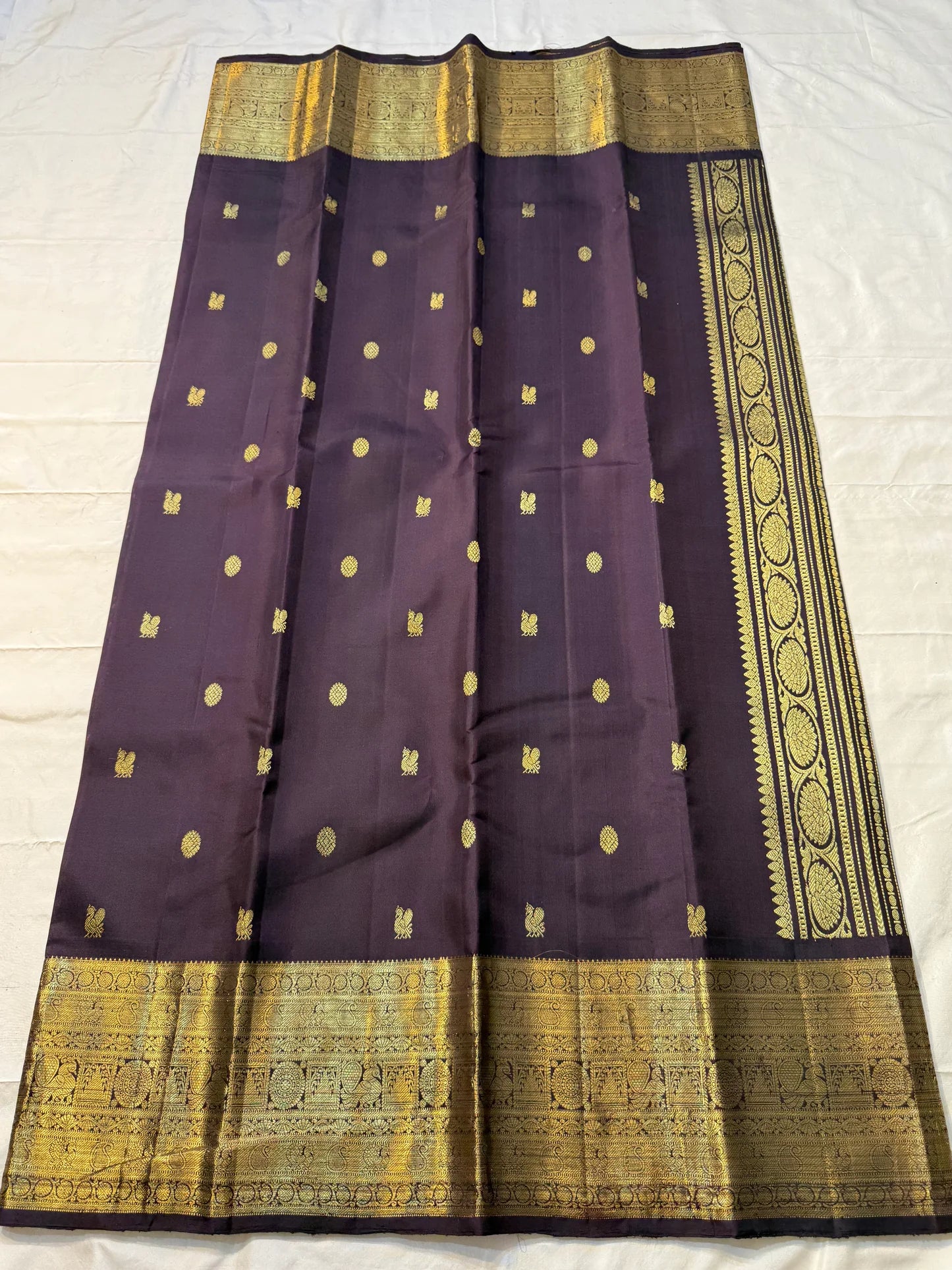 Deep Plum Coin Zari (Pure Kanchipuram Silk)
 Aubergine/plum body with gold chakram & mayil buttas
Self deep-purple border with antique-gold kasu-mālai (coin) motifs
Silk Mark Certified • Free USA Shipping • Ships in Two Weeks