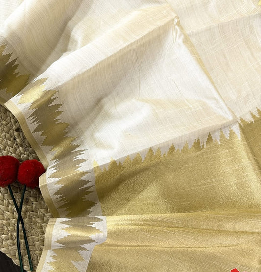 Minimal yet majestic, this ivory-beige silk saree is a celebration of simplicity and sophistication. The body is plain and luminous, texture of the silk shines through. golden zari border with a sharp, zigzag temple-inspired pattern - perfect for Onam