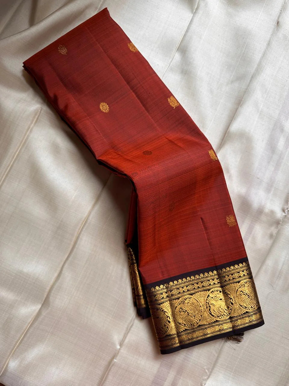 Rust Simha – Pure Silk Kanchipuram Saree
Rust Orange Body with Petite Gold Floral Buttas
Black Korvai Contrast Border with Simha & Annapakshi
Grand Zari Pallu
Comes with Contrast Black Blouse Piece with Zari Border silk Mark certified, ships in 2 weeks