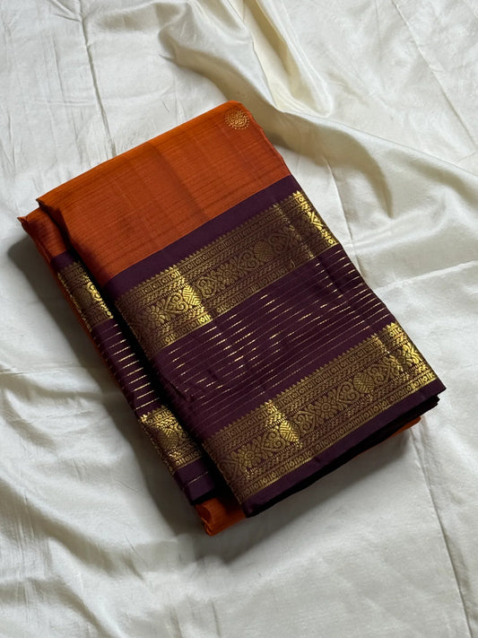 🧡 
Swarnamala — Korvai Kanchipuram Pure Silk
Rust-orange body with radiant gold chakram buttas
Deep purple korvai borders with rich zari detailing
Striped zari brocade pallu with temple-inspired motifs
Silk Mark Certified • Free Shipping within USA