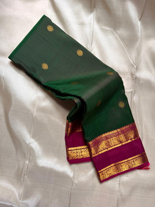 Draped emerald green silk saree showing gold zari buttas and magenta contrast zari border