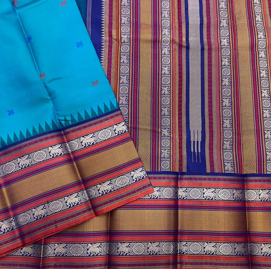 Peacock-teal body with woven silk-thread buttas in navy & coral hues
Korvai contrast ruby-maroon borders with gaja-chakram & temple motifs
Grand varisaipettu striped pallu in navy, mustard & maroon tones
Silk Mark Certified • Ships in Two Weeks