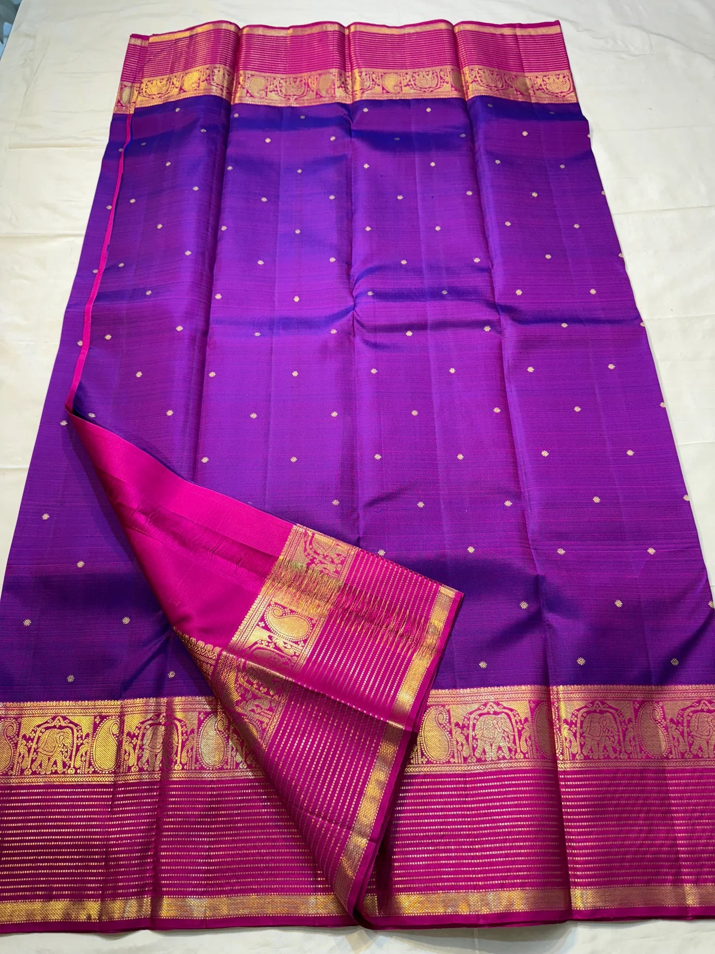 Classic Amethyst — Pure Silk Kanchipuram Saree
Royal violet body with gold muthu buttas & rani-magenta elephant zari borders
Silk Mark Certified • Free USA Shipping • Ships in Two Weeks
