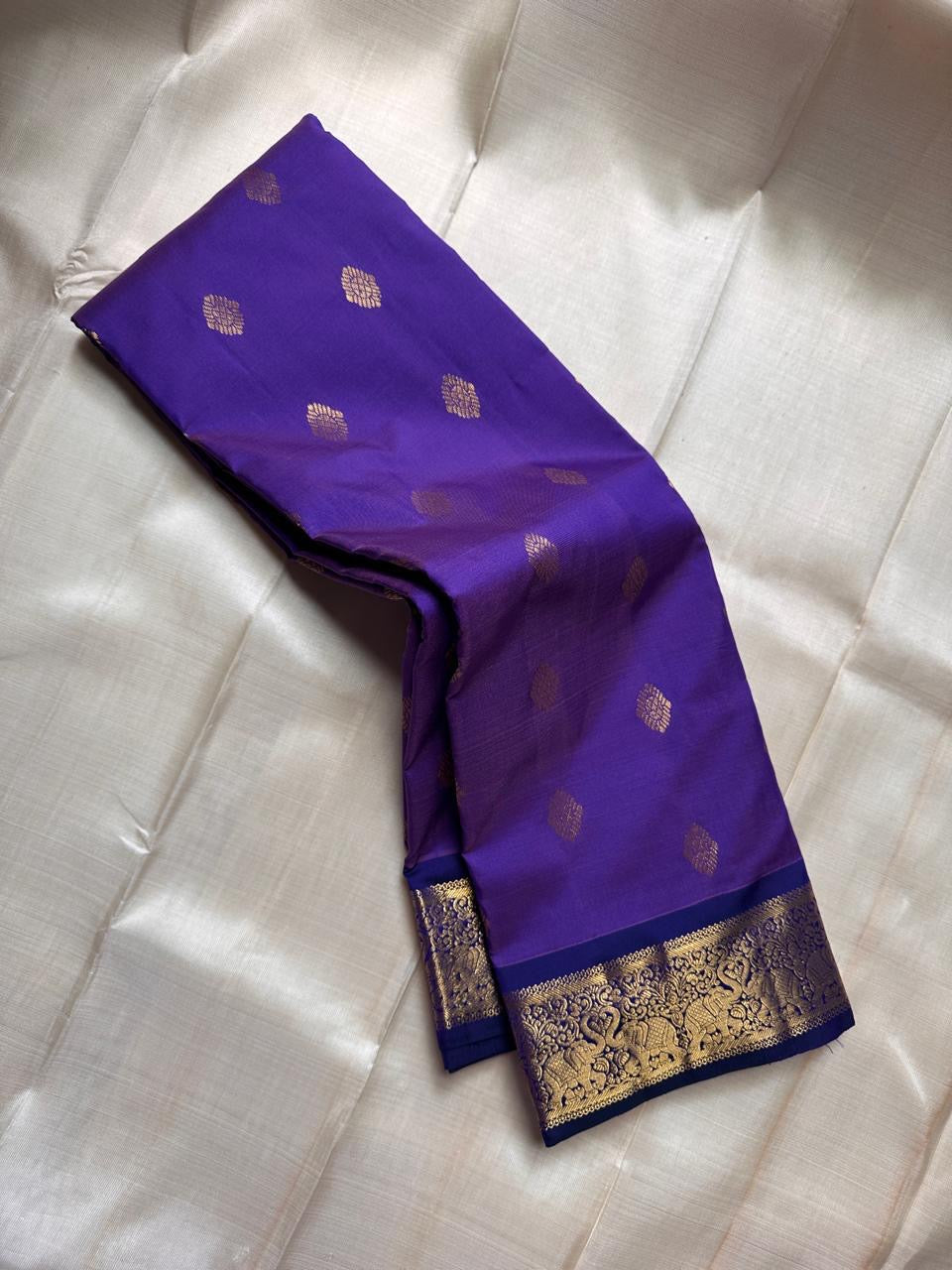 Vadamalli Yaanai – Pure Kanchipuram Silk Saree
Royal purple body with delicate gold zari floral medallion buttas
Ornate yaanai procession borders with vine detailing in zari
Ships in two weeks silk mark certified