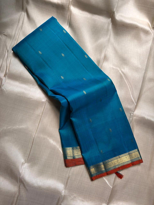 Peacock Teal Ilai Butta – serene teal body with copper-gold zari borders
Pure Kanchipuram silk • dainty leaf (ilai) buttas scattered across the body
Rich teal zari pallu
Silk Mark Certified | Fall & Pico Done | Blouse Stitching Available ($30)