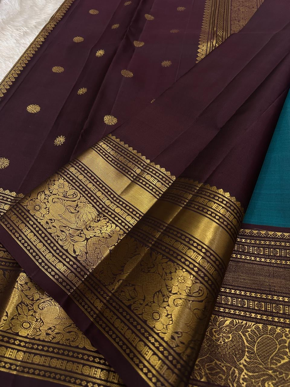 Neeli Megham – Pure Silk Kanchipuram
Teal-blue body with gold annapakshi buttas & aubergine korvai border in antique zari brocade
Silk Mark Certified • Fall & Pico Done • Blouse Stitching Available ($30) • Free Shipping within USA • Ships in Two Weeks