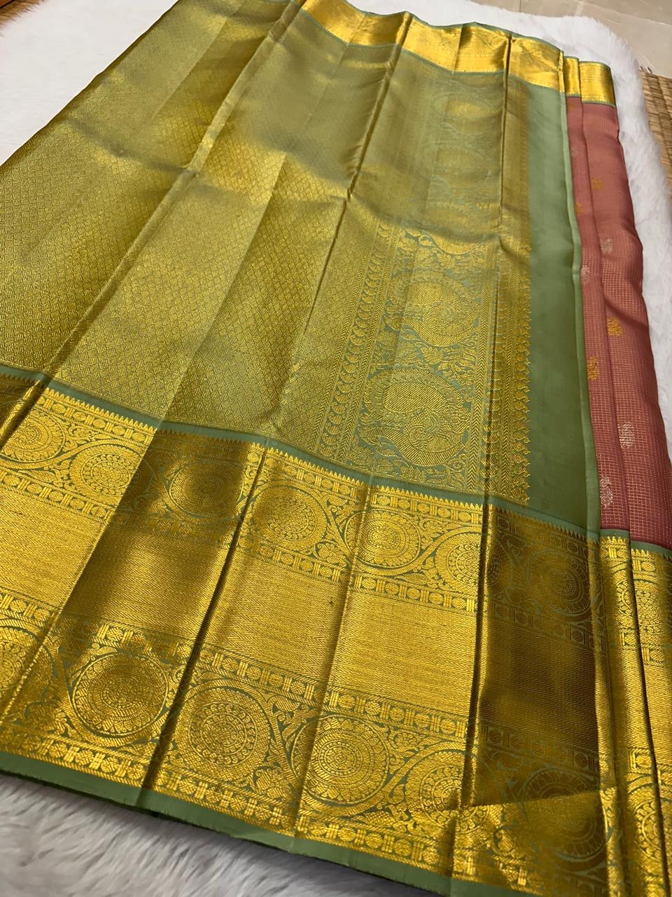 Vahini – Pleasant Peach Pink Pure Kanchipuram Silk Saree with Zari Kattam Checks, Silver & Gold Peacock Buttas, Sage Green Border Adorned with Kamalam Vines and Baavanji Motifs, and an Ornate Zari Pallu with Majestic Peacocks