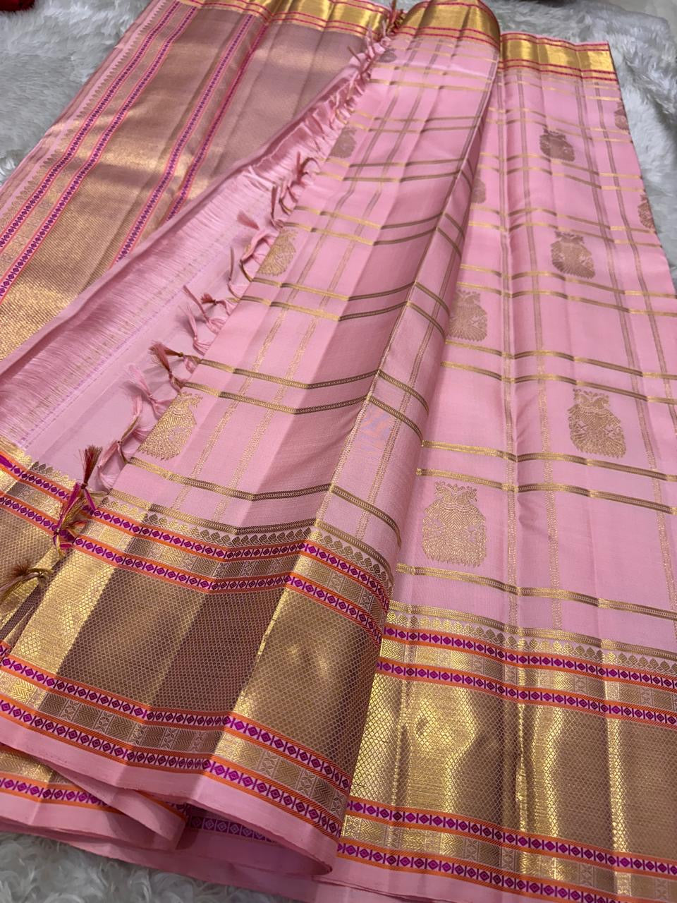 Rose-Quartz Kattam — Kanchipuram Pure Silk  Pastel baby-pink body with windowpane checks (checks )  Minimal zari buttas scattered across the body  Broad gold kaddi borders with pink meenakari accents  Silk Mark Certified | Free Shipping within USA