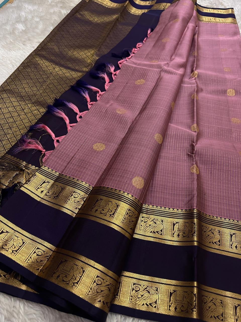 Midnight Blue & Mauve — Pure Silk Kanchipuram
Mauve body with pin-stripes & zari coin buttas ✨
Midnight-navy korvai borders with gaja panels 🌸
Grand navy brocade pallu with tassels 🪔
Silk Mark Certified • Free Shipping USA • Ships in Two Weeks ✅