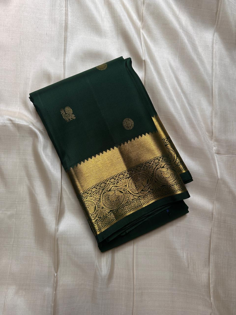Agnika – Green Kanchipuram Silk Saree with Mayil Chakram Butta
Fiery and regal, Agnika features a rich green silk body with intricate Mayil Chakram (peacock) motifs and a shimmering zari border—an elegant ode to South Indian tradition.
