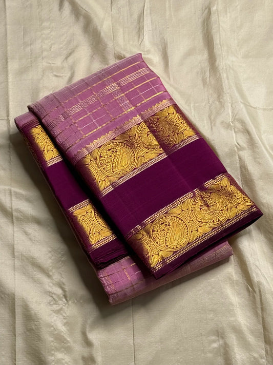 Mauve Mayil Mukham — Kanchipuram Pure Silk
Pastel-mauve pink  body with delicate zari wide kattam checks
Deep plum korvai border with grand mayil (peacock) chakram motifs
Copper-rose chevron zari pallu & plum contrast blouse
Silk Mark Certified • Free