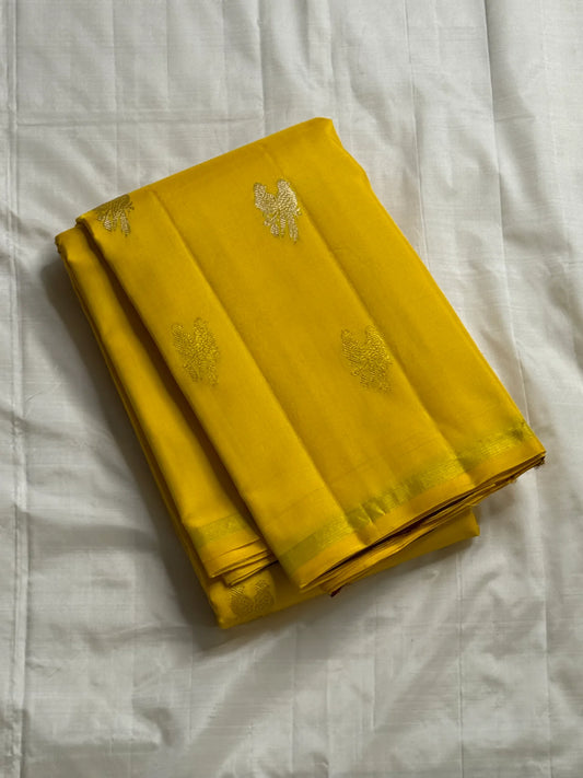 Kanaka Mayuri — Pure Silk Kanchipuram Saree
Haldi / Marigold Yellow with Silver-Zari Peacock Buttas ✨
Minimal Self Borders • Contrast Plum Brocade Pallu 💜
Handwoven in Pure Mulberry Silk | Silk Mark Certified ✅
Ships in Two Weeks Free | Idam Living
