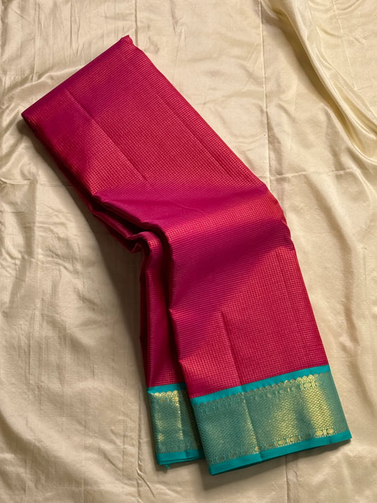 Leela Kattam — Kanchipuram Pure Silk
Rani-pink micro kattam body with soft vaira-oosi sheen
Contrast teal korvai borders with gold lattice & coin roundels
Rich teal pallu with all-over diamond/leaf zari jaal; rani tassels
Silk Mark Certified •