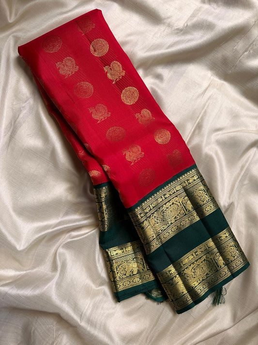 Jyoti – Radiant Tomato Red Kanchipuram Pure Silk Saree
With Mayil 🦚 Chakram ⚙️ Buttas Woven All Over
Rettapet Green Vanasringaram Zari Border 🌿
Handwoven Heritage | Silk Mark Certified