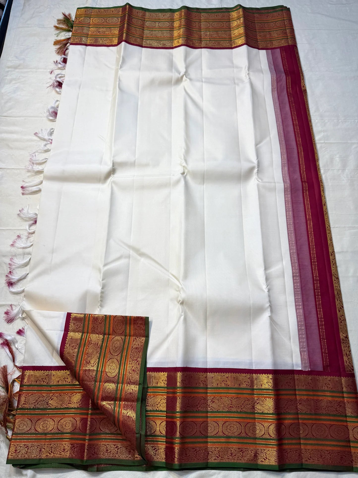 Shveta Chakram — Ivory Kanchipuram Pure Silk 🤍
Contrast maroon brocade pallu & temple border ✨
Chakra medallions, floral vines + green selvedge 🌿
Orange pin-stripes on the border; tasselled finish 🪔
Silk Mark Certified • free shipping with Usa with