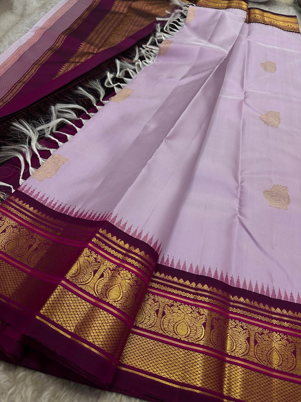 Lavanya Varnam — Pure Silk Kanchipuram Saree
Soft lavender-lilac body with rose-gold paisley buttas and deep wine-maroon korvai borders woven with temple motifs and rich zari.
Silk Mark Certified • Blouse Stitching Available ($30) • Free USA Shipping •