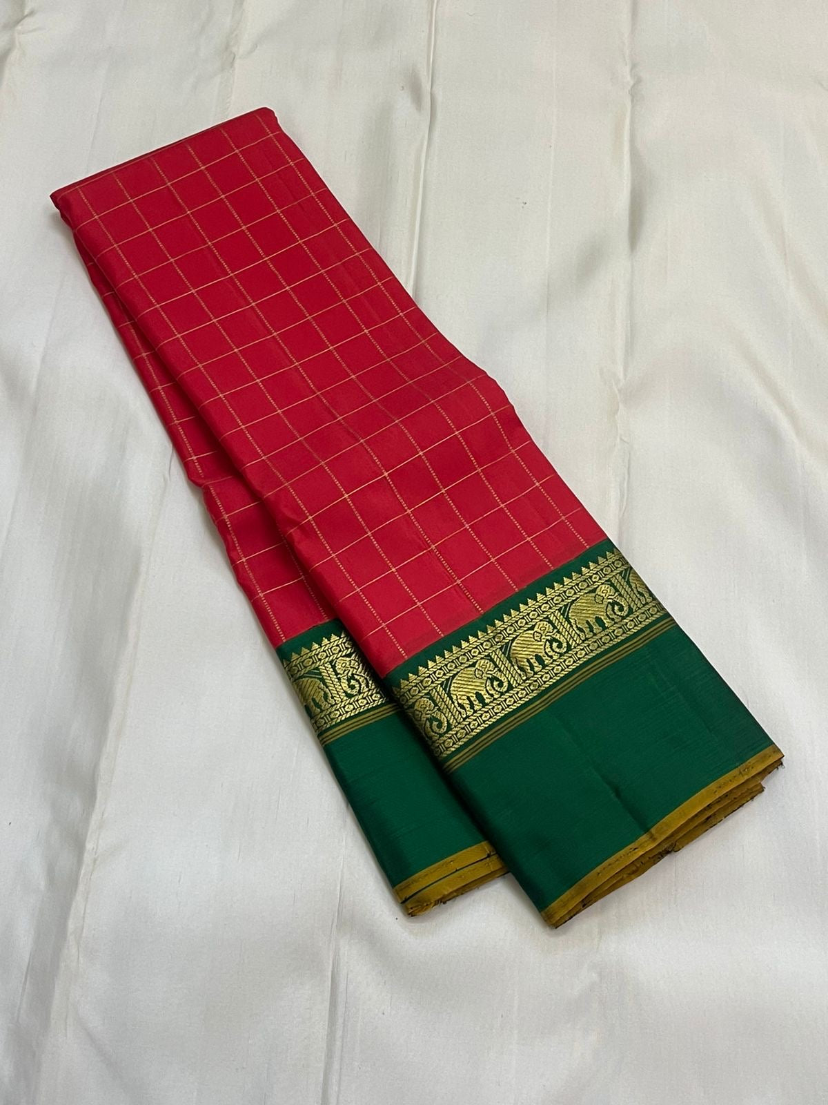 Emerald Ruby Korvai
Pure Kanchipuram Silk Saree – Ruby Red Body with muthu kattam Grid Checks
Emerald Green Korvai Borders Adorned with Zari Elephant Motifs
Grand Green Zari seer Pallu with Traditional motifs
Silk mark certified, ships in 2 weeks