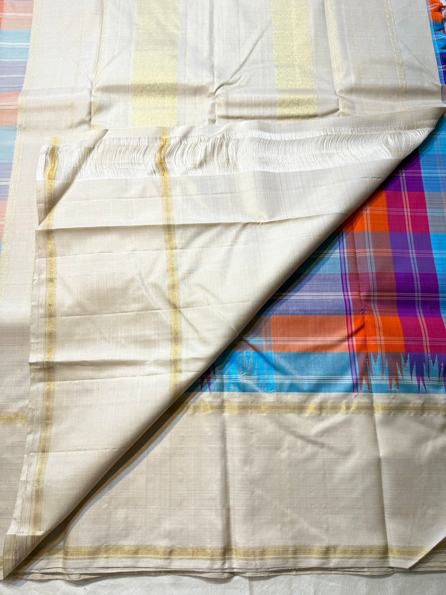 Venpattu Kattam Thazampoo Reku – ivory/venpattu borders with multicolor kattam (checks) body
Pure Kanchipuram silk • rani pink, tangerine, purple, sky blue & steel grey checks with thazampoo reku edging
Ivory pallu with gold tissue stripes & multicolor