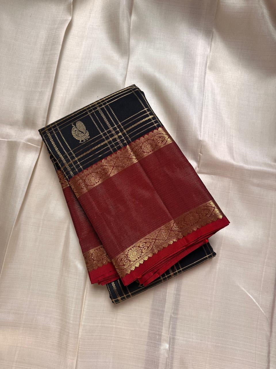 Kanmani Karuppu Kattam Ruby – Pure Kanchipuram Silk Saree
Deep black body with gold kattam checks & peacock buttas
Contrast ruby-red korvai borders
Grand ruby-red pallu with floral & lattice zari motifs
Silk Mark Certified | ships in 2 weeks