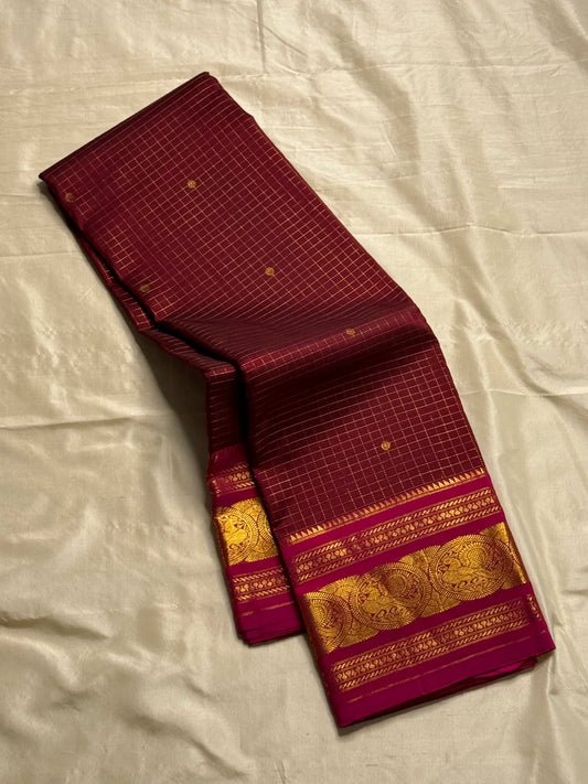 Arakku Kattam Mayura Chakram – Pure Silk Kanchipuram Saree (Maroon & Rani Pink)
Micro-check body with tiny gold buttas; vibrant rani contrast
Antique-gold peacock chakram border & grand woven zari pallu
Silk Mark Certified | Blouse Piece Included |