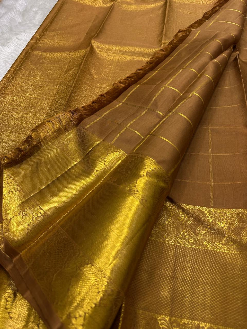 Bronze Chakram — Kanchipuram Pure Silk
Warm caramel-brown body with grid checks & “chakram” buttas
Grand gold zari peacock border & glowing pallu (kaddi + paisley vine)
Silk Mark Certified | Free Shipping within USA
Dispatch in 1 Week