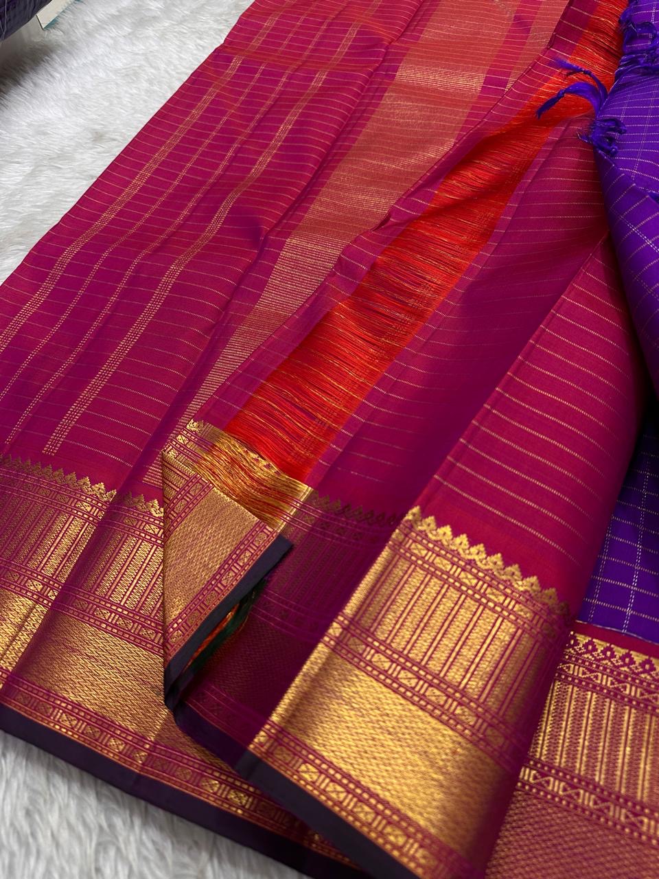 Amethyst Zari Kattam – Pure Kanchipuram Silk Saree
Rich Amethyst Purple Body with Golden Zari Checks
Broad Gold Zari Border with Red Highlights & Temple Motifs
Radiant Ruby Red-Orange Pallu with Lustrous Zari Stripes
Silk Mark Certified, delivery in 2 we