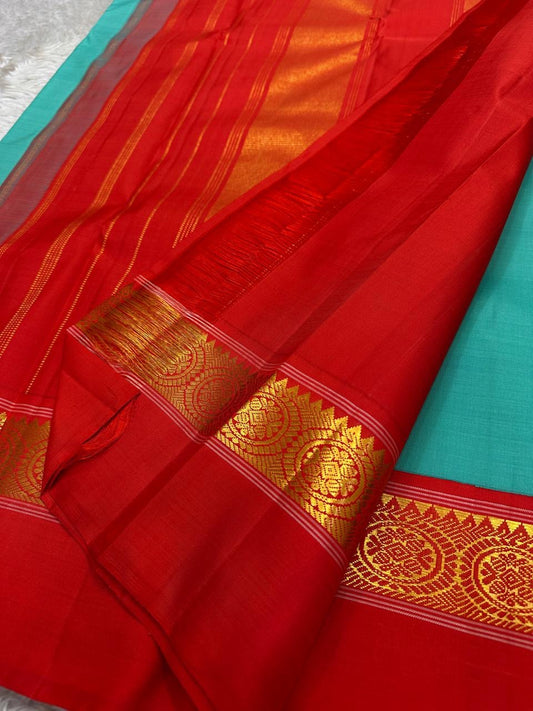 Pure Kanchipuram silk saree in Rama green with vibrant red kaal erangina border and intricate gold zari work, displayed partially open.