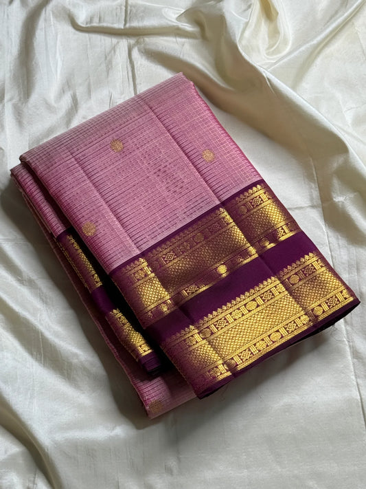 Rose Mist Zari Kattam — Kanchipuram Pure Silk
Blush rose-pink body with micro kattam (checks) in zari & scattered soorya-chakram buttas
Contrast mulberry purple korvai borders with rich gold zari detailing
Free shipping within USA silk mark certified
