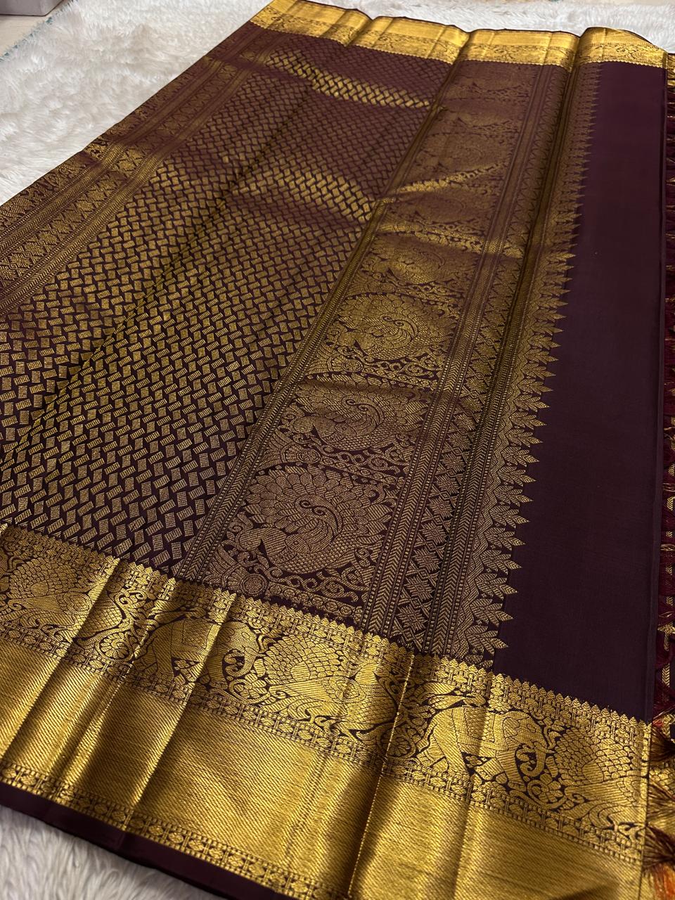Ambaram – Coffee Brown
 — Pure Kanchipuram Silk
Elephant & Peacock Procession Zari Border • Coin & Gandaberunda Buttas
Geometric Diamond Brocade Pallu in Antique Gold
Handloom •
Silk Mark Certified • Ships in Two Weeks