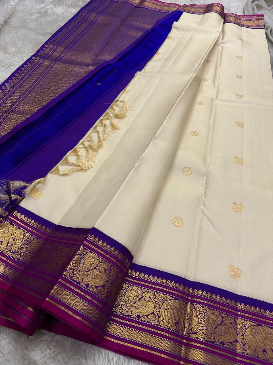 ⸻
Ivory Glow ✨ – Pure Kanchipuram Silk Saree in Ivory
Korvai Royal-Purple Border with Elephant & Peacock Zari Panels; Magenta Selvedge
Body with Gold Coin & Paisley Buttas
Grand Royal-Purple Brocade Zari Pallu with Hand-knotted Tassels