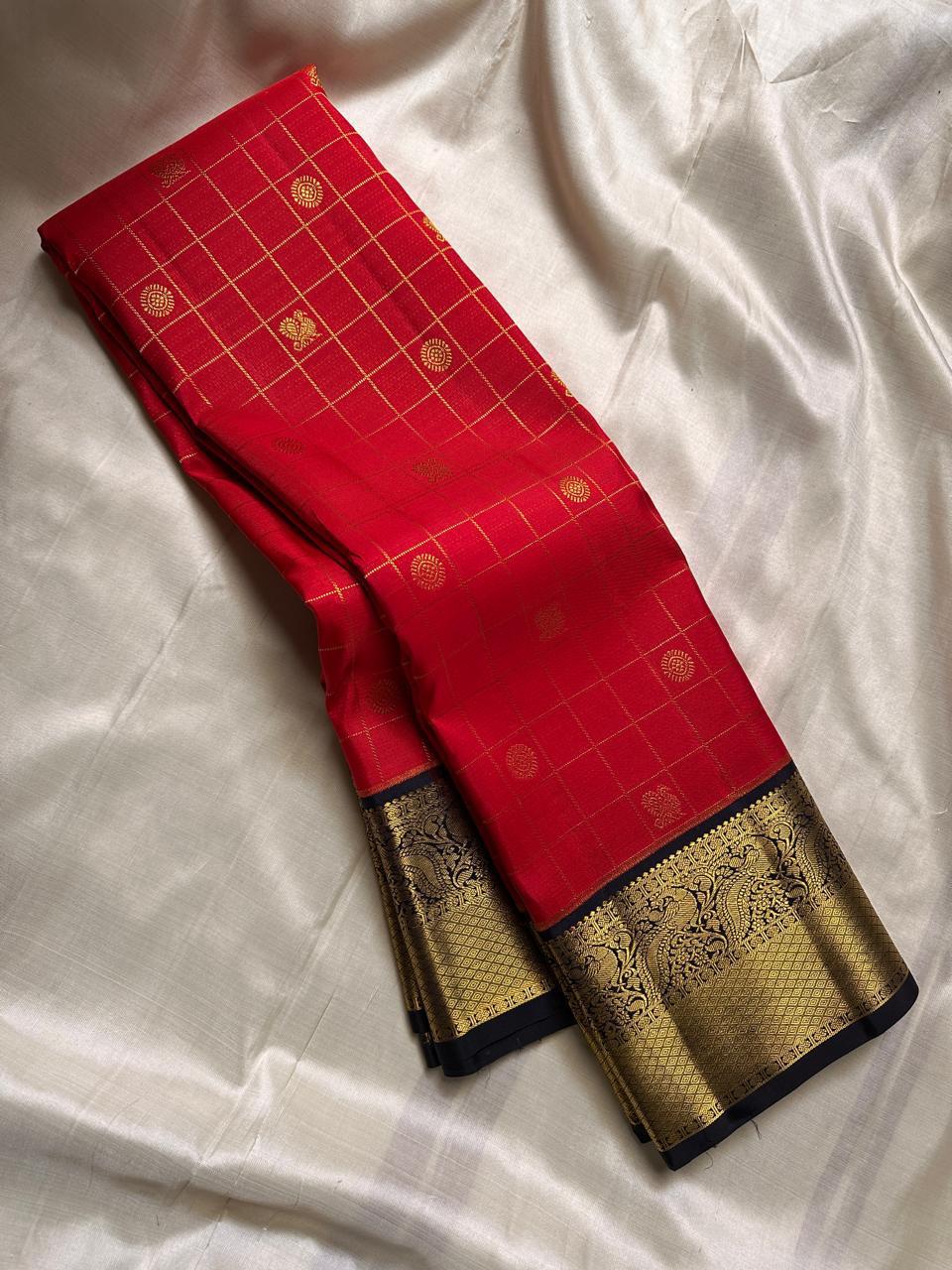 Ranga - A vivid red pure silk Kanchipuram saree featuring intricate zari kattam with traditional mayil, chakram, butta, and vanasringaram motifs across the body. The contrast jamun dark blue border and pallu are woven with exquisite Annam motifs