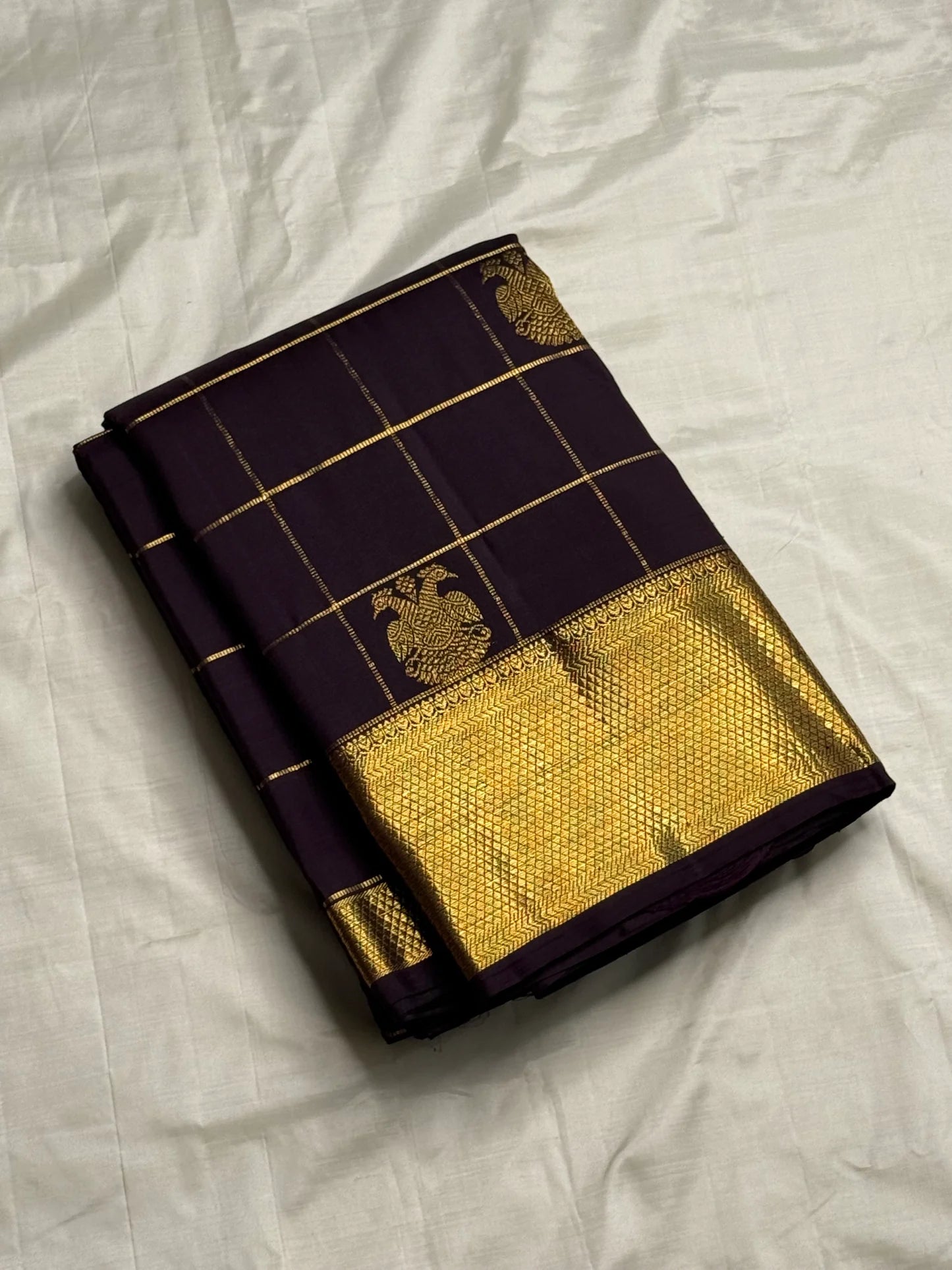 Plum Zari Kattam — Pure Kanchipuram Silk Saree
Rich plum body with gold kattam grid & Gandaberunda buttas ✨
Antique-gold brocade border & grand zari pallu • Silk Mark Certified • Free Shipping within USA • Ships in Two Weeks