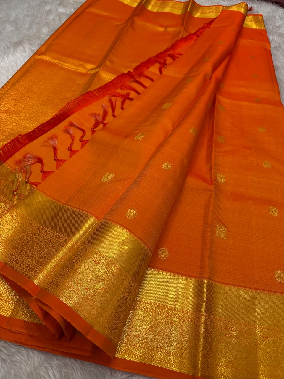 Agnika – orange Kanchipuram Silk Saree with Mayil Chakram Butta & Orange Border Fiery and regal, Agnika is a pure Kanchipuram silk saree featuring a rich red body adorned with intricate Mayil Chakram buttas.