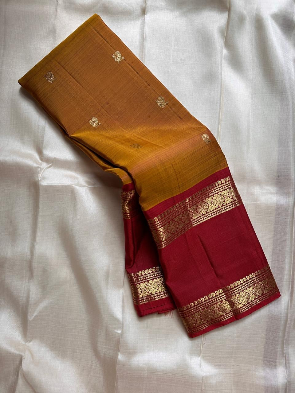Ponvandu Kumkumam – Pure Kanchipuram Silk Saree
Honey-Gold Body with Zari Buttas
Contrasting Kumkum Red Borders with Floral Zari
Grand Kumkum Red Pallu with Zari Kaddi & Brocade
Silk Mark , | ships in 2 weeks, fall pico | Blouse Stitching Available |