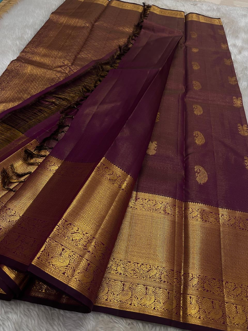 Varnika – Handwoven Kanchipuram Silk Saree in Plum Wine
A regal plum Kanchipuram silk saree adorned with gold zari paisleys and Gandaberunda motifs