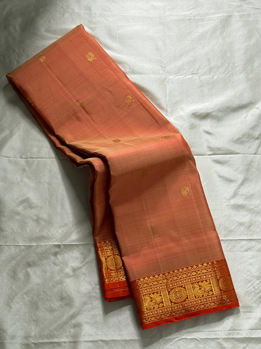 Mandara Peach – Pure Korvai Kanchipuram Silk Saree
Soft peach shot body with dainty gold chakram buttas
Vermilion-orange korvai borders with peacock medallions
Grand kumkumam red pallu with full zari brocade & temple panels
Silk Mark Certified | Free Ship