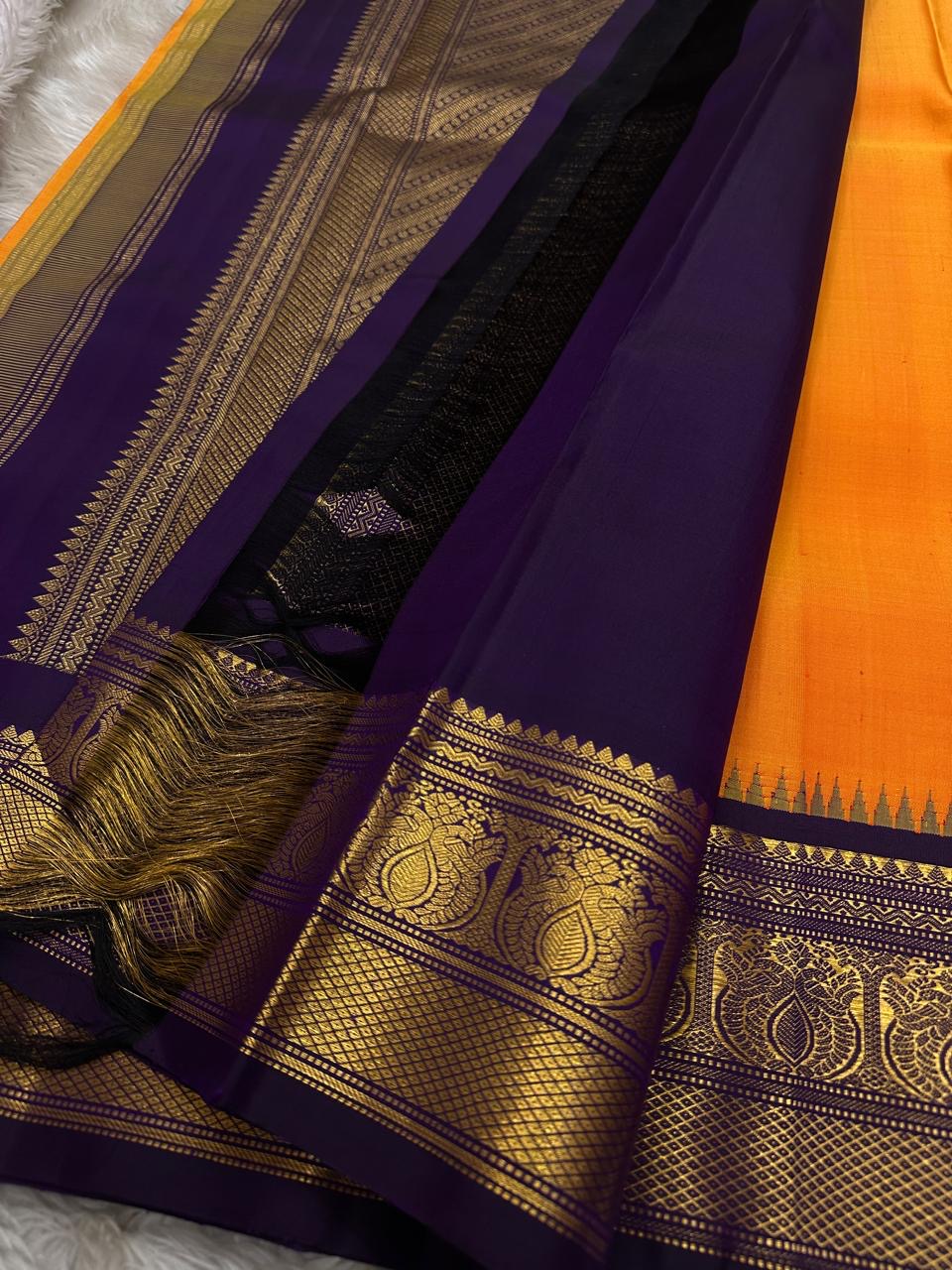 Pure Kanchipuram Silk Saree – Saffron-Orange Body with Gold Zari Paisley Buttas
Contrast Deep Purple Korvai Borders with Intricate Temple & Floral Motifs
Grand Purple Zari Pallu with Diagonal zariWeave . Silk mark , ships in 2 weeks