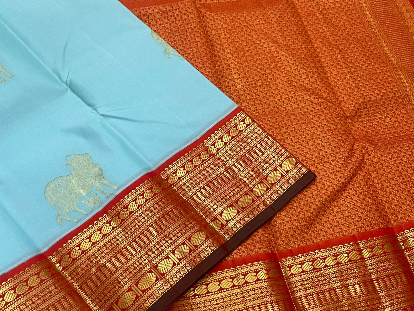 Kamadhenu — Pure Silk Kanchipuram
Sky-blue body with gold Kamadhenu motifs, fiery-orange pallu & ruby-red korvai borders ✨
Silk Mark Certified • Antique Zari Weave • Ships in Two Weeks • Free Shipping within USA
